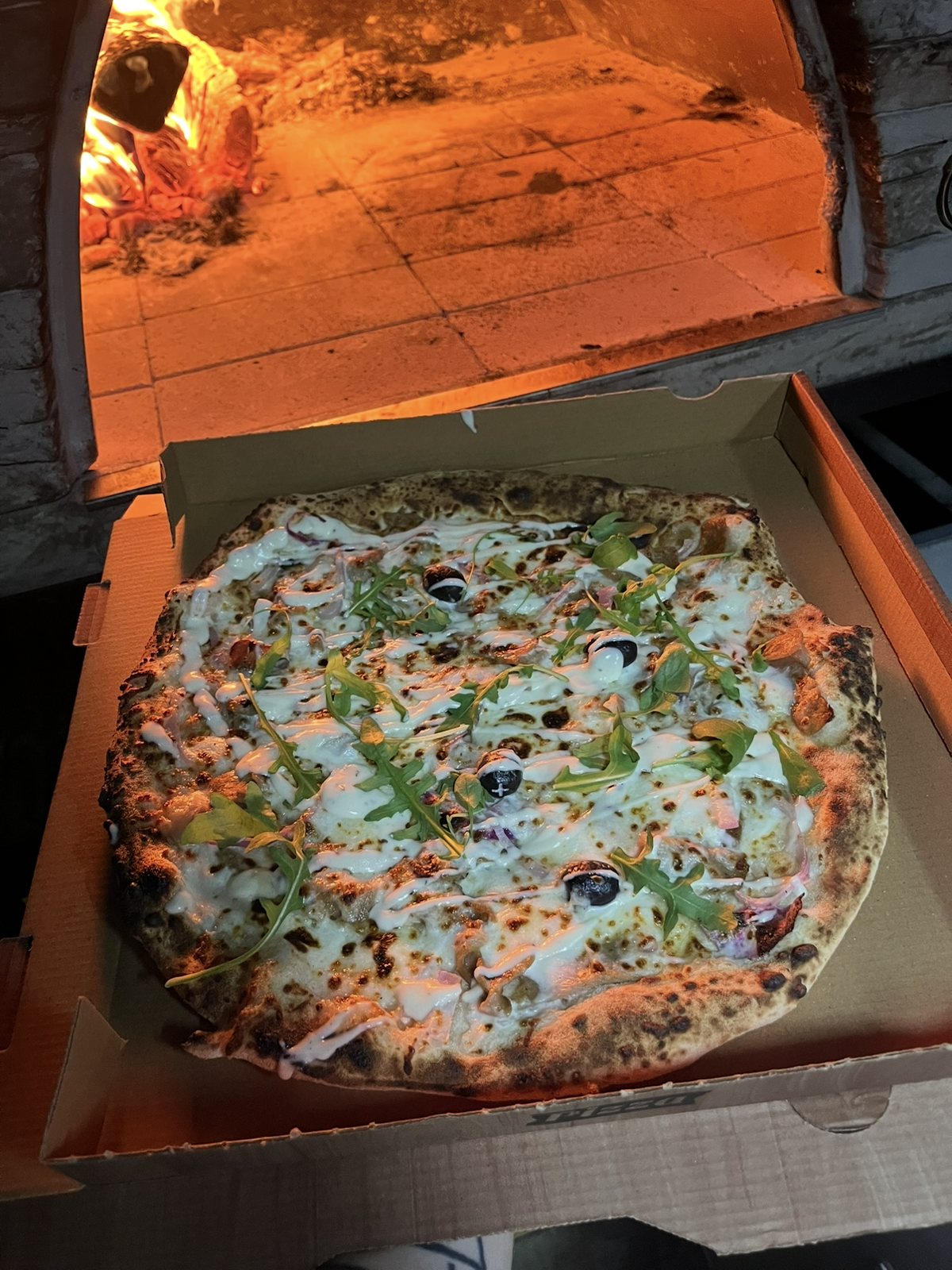 Pizza sortie du four à bois, dans sa boîte